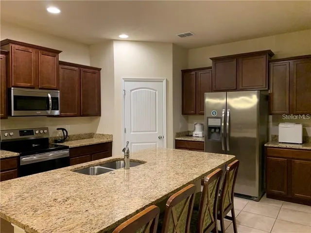 a kitchen with stainless steel appliances wooden cabinets a sink and a refrigerator
