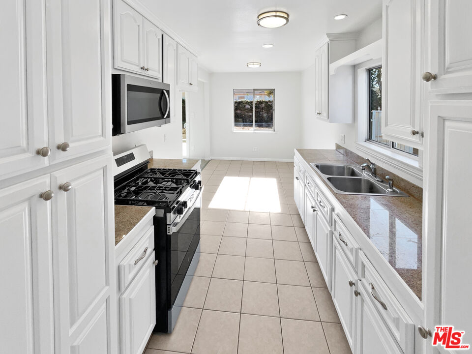 1616 West Piru Street Compton, CA 90222 - Photo 15 of 19 a kitchen with a stove a sink and a microwave