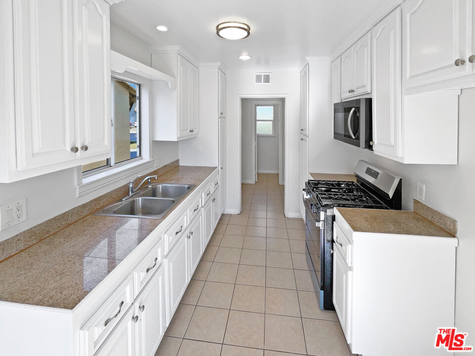 1616 West Piru Street Compton, CA 90222 - Photo 6 of 19 a kitchen with granite countertop a sink a stove and refrigerator