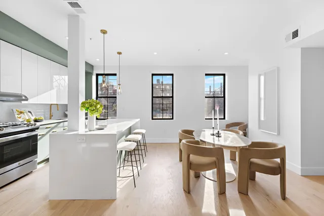 a kitchen with stainless steel appliances kitchen island granite countertop a table chairs stove and white cabinets