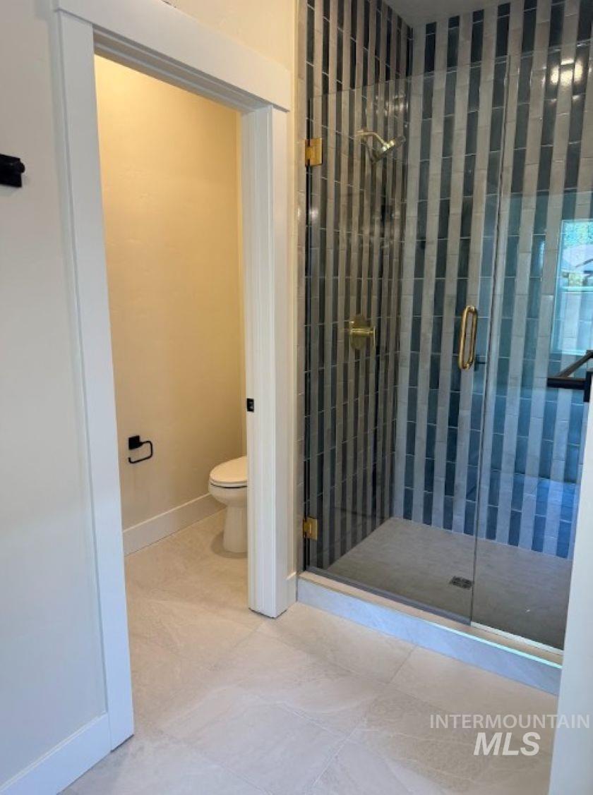 683 West Wrangler Street Meridian, ID 83646 - Photo 12 of 23 Glass-enclosed shower with vertical striped tile, gold-tone fixtures, and a clear glass door