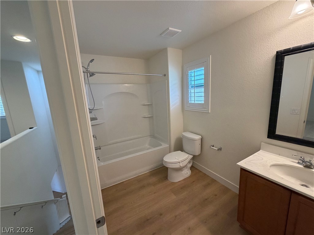 7879 Shoreline Ridge Court Las Vegas, NV 89166 - Photo 15 of 26 Gleaming wood-look floors pair with clean white finishes in this well-appointed bathroom.