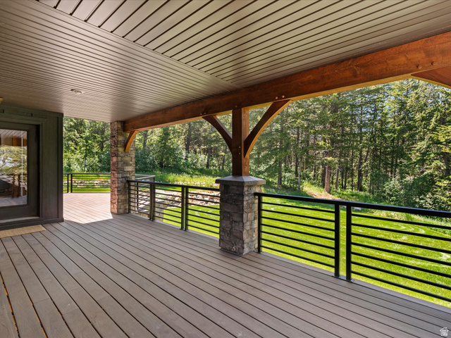 1225 Old Oregon Road Soda Springs, ID 83276 - Photo 43 of 67 Spacious covered deck featuring composite decking, stone columns, horizontal metal railings, and exposed wood beam accents