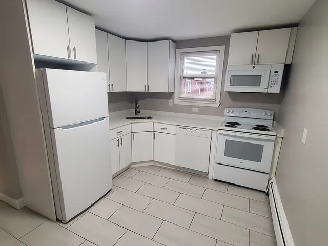 a kitchen with white cabinets and white appliances