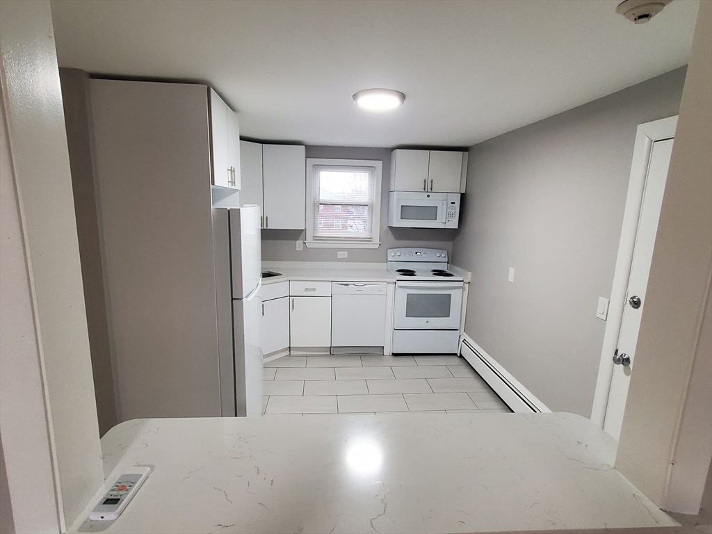 433 B Sea Street, Unit 5 Quincy, MA 02169 - Photo 2 of 14 a kitchen with white cabinets and white appliances