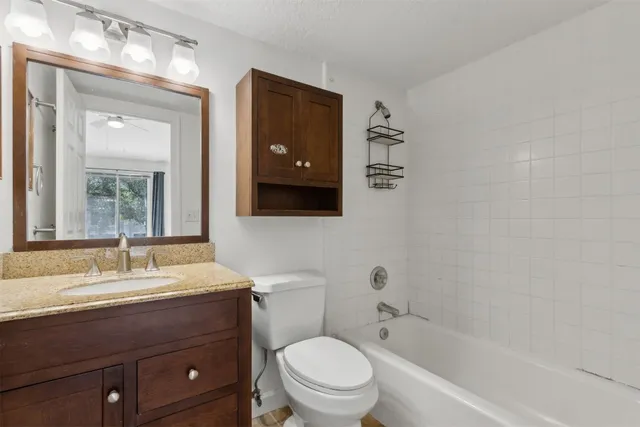 a bathroom with a granite countertop toilet sink and mirror