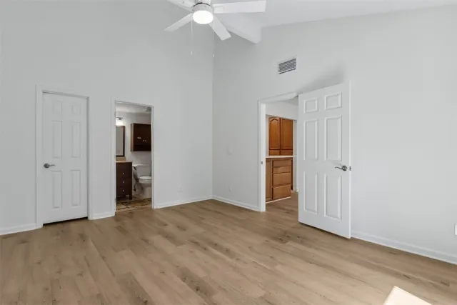 an empty room with wooden floor closet and windows