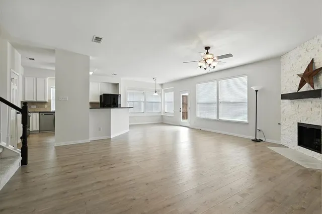 a view of empty room with wooden floor and a kitchen