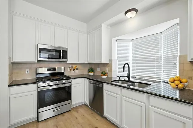 a kitchen with granite countertop a sink stainless steel appliances and cabinets