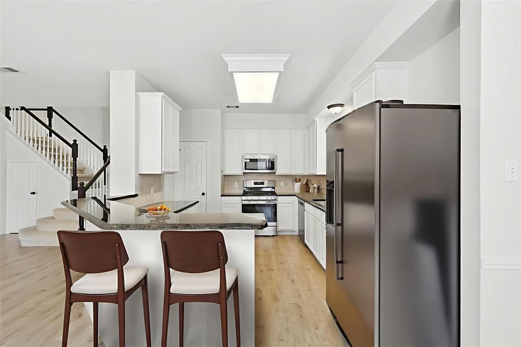 5713 Green Hollow Lane The Colony, TX 75056 - Photo 13 of 29 a kitchen with stainless steel appliances granite countertop a refrigerator a sink a stove and chairs