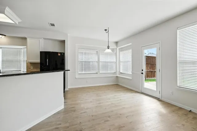 a view of an empty room with a window and a kitchen