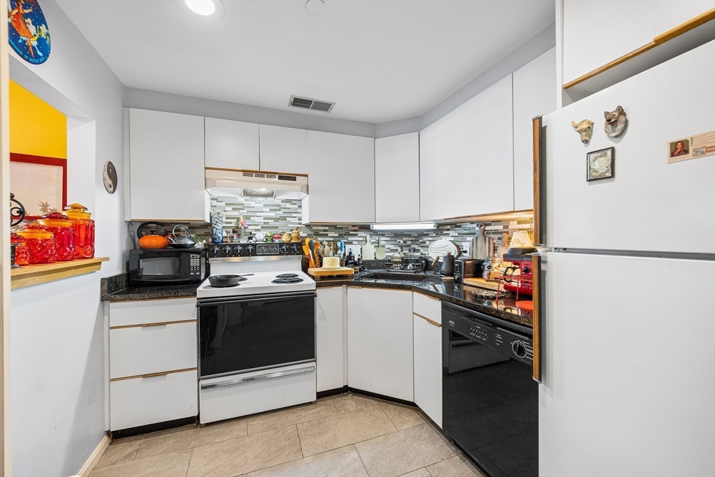 315 Rantoul Street, Unit 402 Beverly, MA 01915 - Photo 6 of 27 a kitchen with granite countertop white cabinets and white appliances