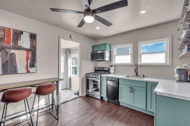 a kitchen with stainless steel appliances granite countertop a sink a stove a refrigerator cabinets and wooden floor