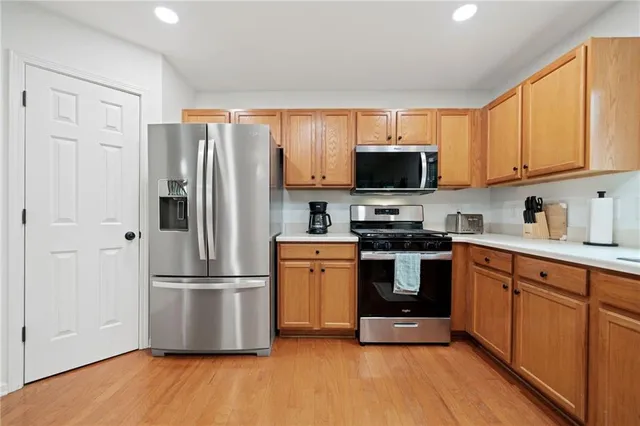 a kitchen with granite countertop a refrigerator stove top oven a sink and dishwasher with wooden floor