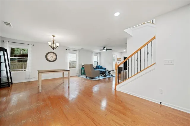 a living room with couches chandelier and a dining table with wooden floor