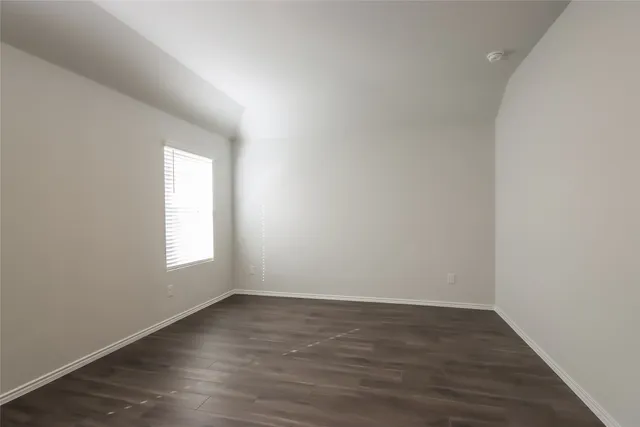 an empty room with wooden floor and window