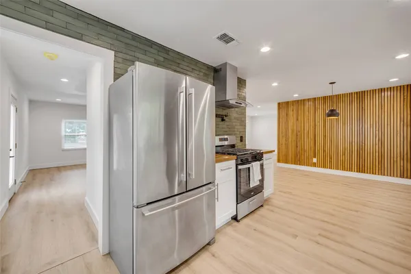 a kitchen with stainless steel appliances a refrigerator and wooden floor