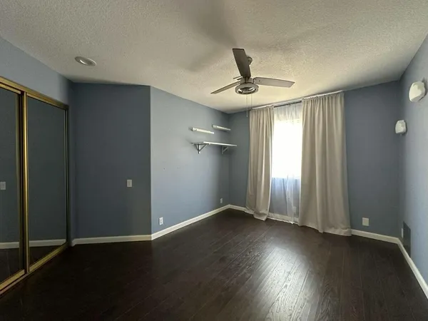 an empty room with wooden floor fan and windows