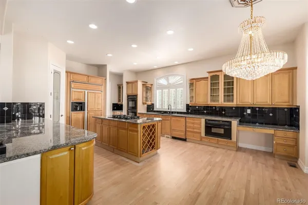 a large kitchen with stainless steel appliances granite countertop a stove and a wooden floors