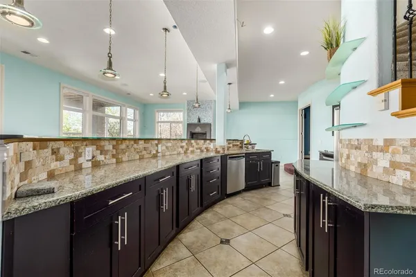 a large kitchen with a large counter top a sink a counter space and stainless steel appliances