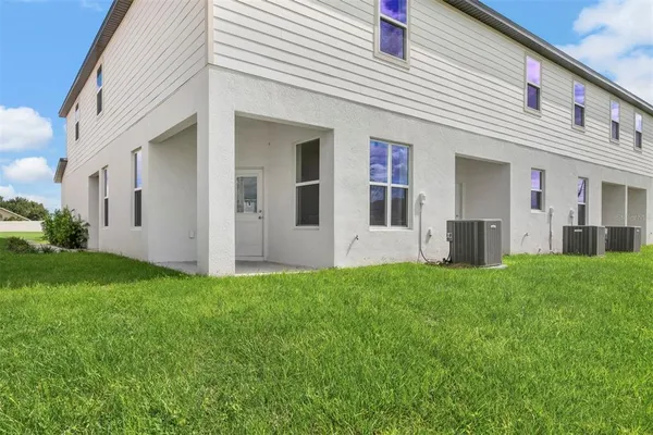 a view of a white house with a big yard and large trees