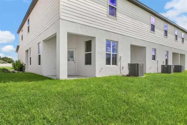 a view of a white house with a big yard and large trees