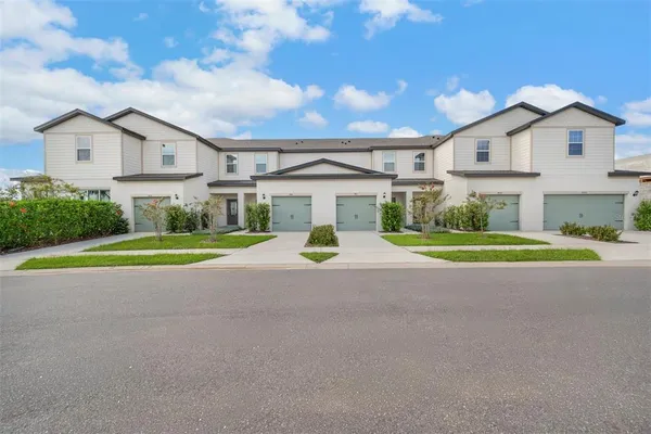 a view of a white house with a big yard and large trees