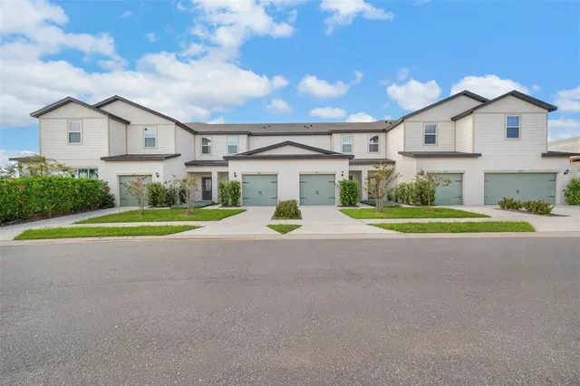 a view of a white house with a big yard and large trees