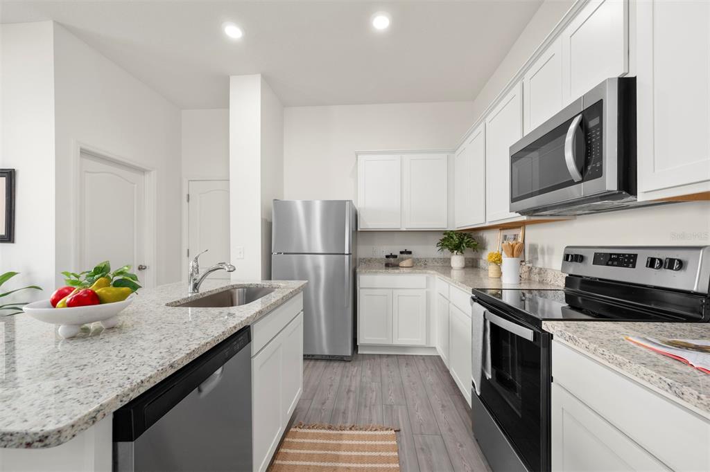 727 Poppy Lane Dundee, FL 33838 - Photo 5 of 31 a kitchen with stainless steel appliances granite countertop a sink stove and refrigerator