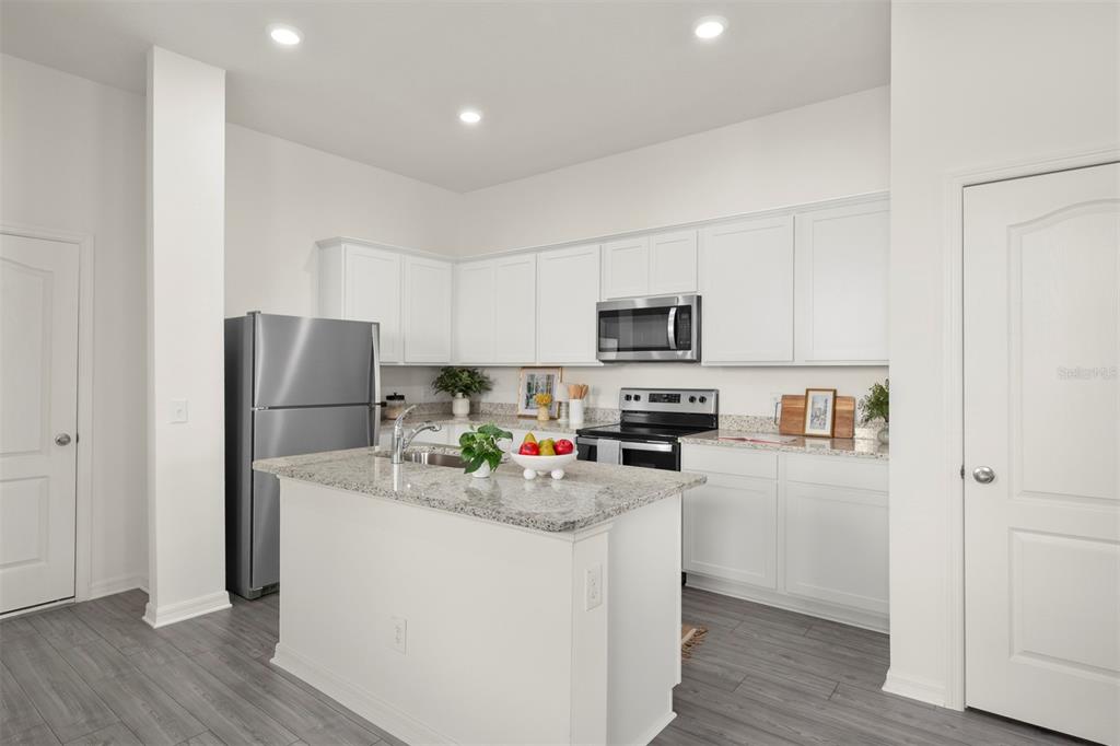 727 Poppy Lane Dundee, FL 33838 - Photo 6 of 31 a kitchen with stainless steel appliances a refrigerator stove microwave and sink