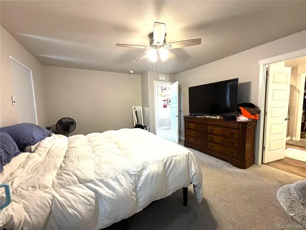 a bedroom with bed tv and wooden floor