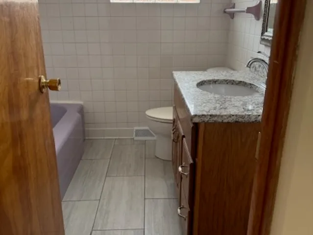 a bathroom with a granite countertop sink and a toilet