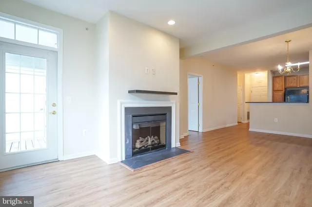 a view of an empty room with wooden floor fireplace and a window