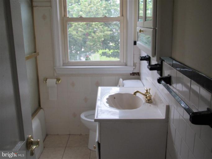 5900 Hillen Road Baltimore, MD 21239 - Photo 4 of 11 a bathroom with a sink a toilet and a window