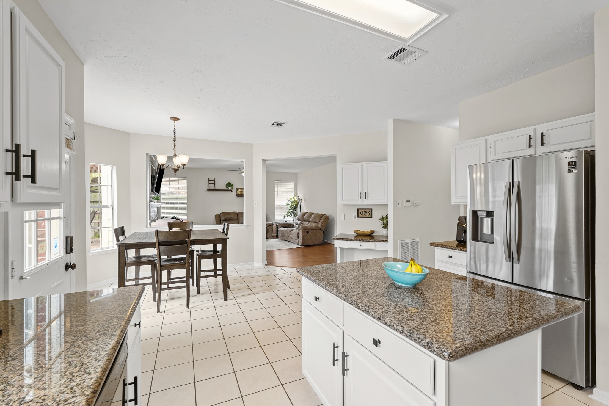 16114 Kintyre Point Road Houston, TX 77095 - Photo 24 of 44 This bright kitchen features granite countertops, white cabinetry, and stainless steel appliances. It opens to a dining area with a large window and flows into a cozy living space, creating an inviting open-concept feel.