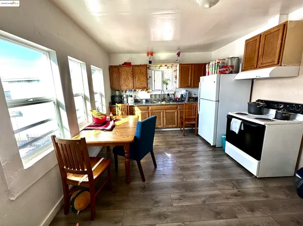 a kitchen with a stove a sink dishwasher and a dining table with wooden floor