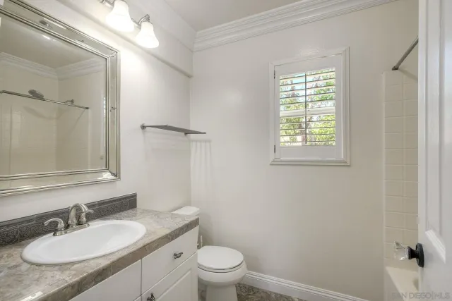 a bathroom with a granite countertop sink toilet a mirror and shower