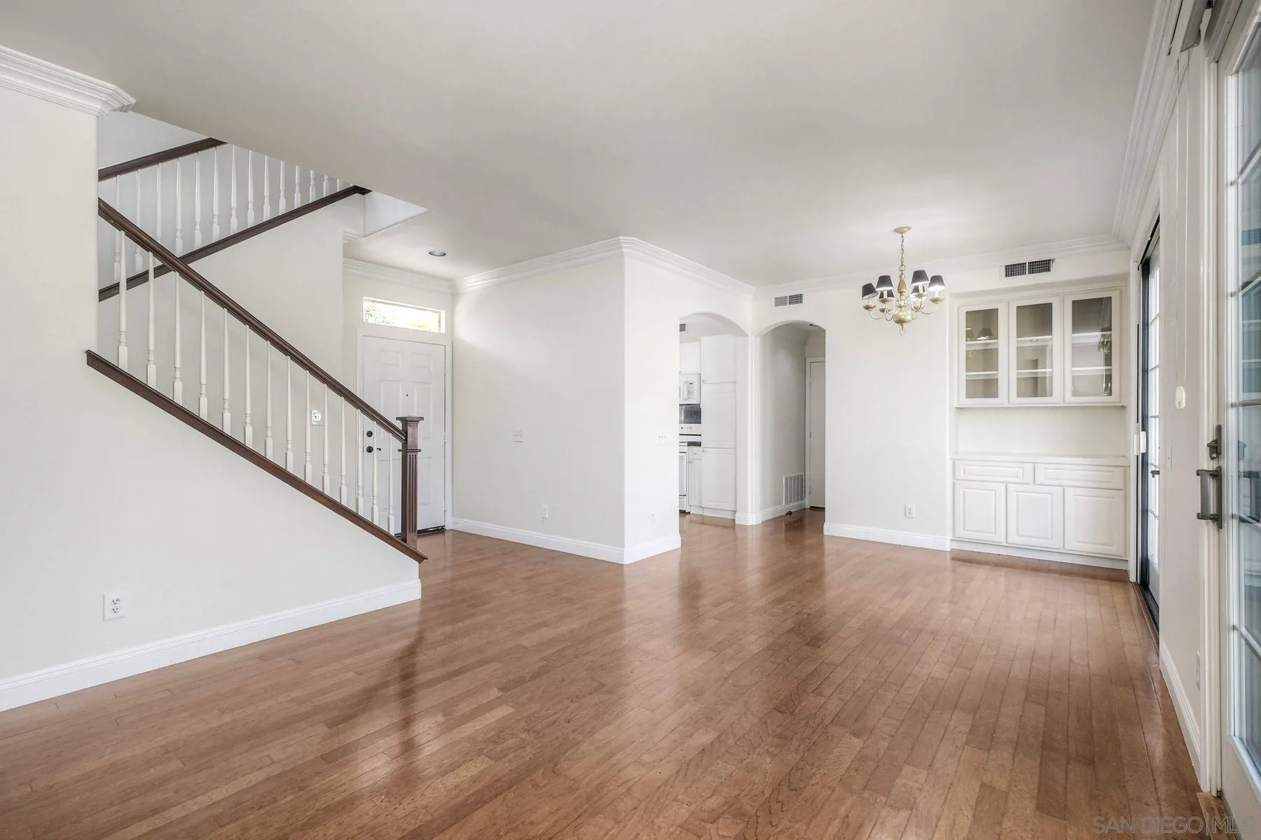 9633 Stonecrest Boulevard San Diego, CA 92123 - Photo 9 of 45 a view of an empty room with wooden floor and a kitchen