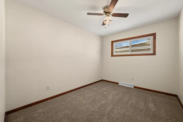 an empty room with a fan & a ceiling fan