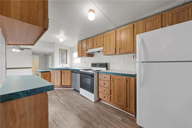 a kitchen with granite countertop a refrigerator a sink dishwasher a stove top oven a refrigerator and cabinets