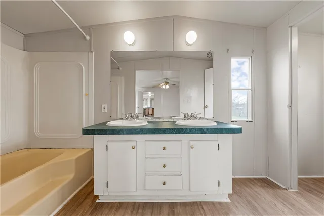 a bathroom with a granite countertop bathtub a sink and a mirror
