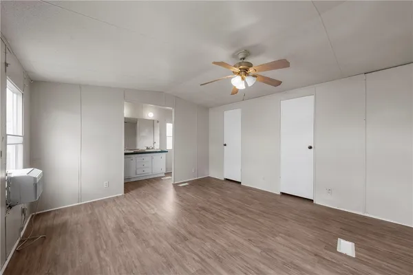 a view of an empty room with a window and wooden floor