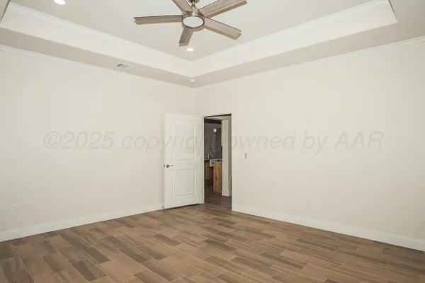 an empty room with wooden floor ceiling fan and windows