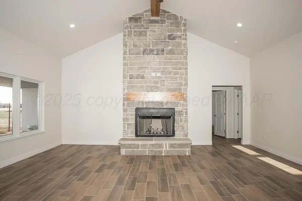 an empty room with wooden floor fireplace and windows