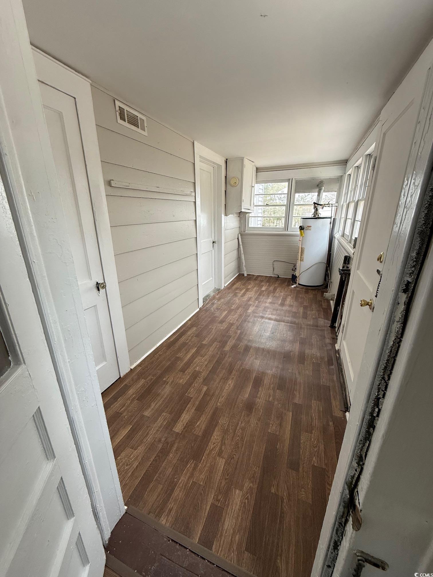 305 East Bamberg Street Latta, SC 29565 - Photo 12 of 13 Hall featuring dark wood-type flooring, gas water heater, and wooden walls