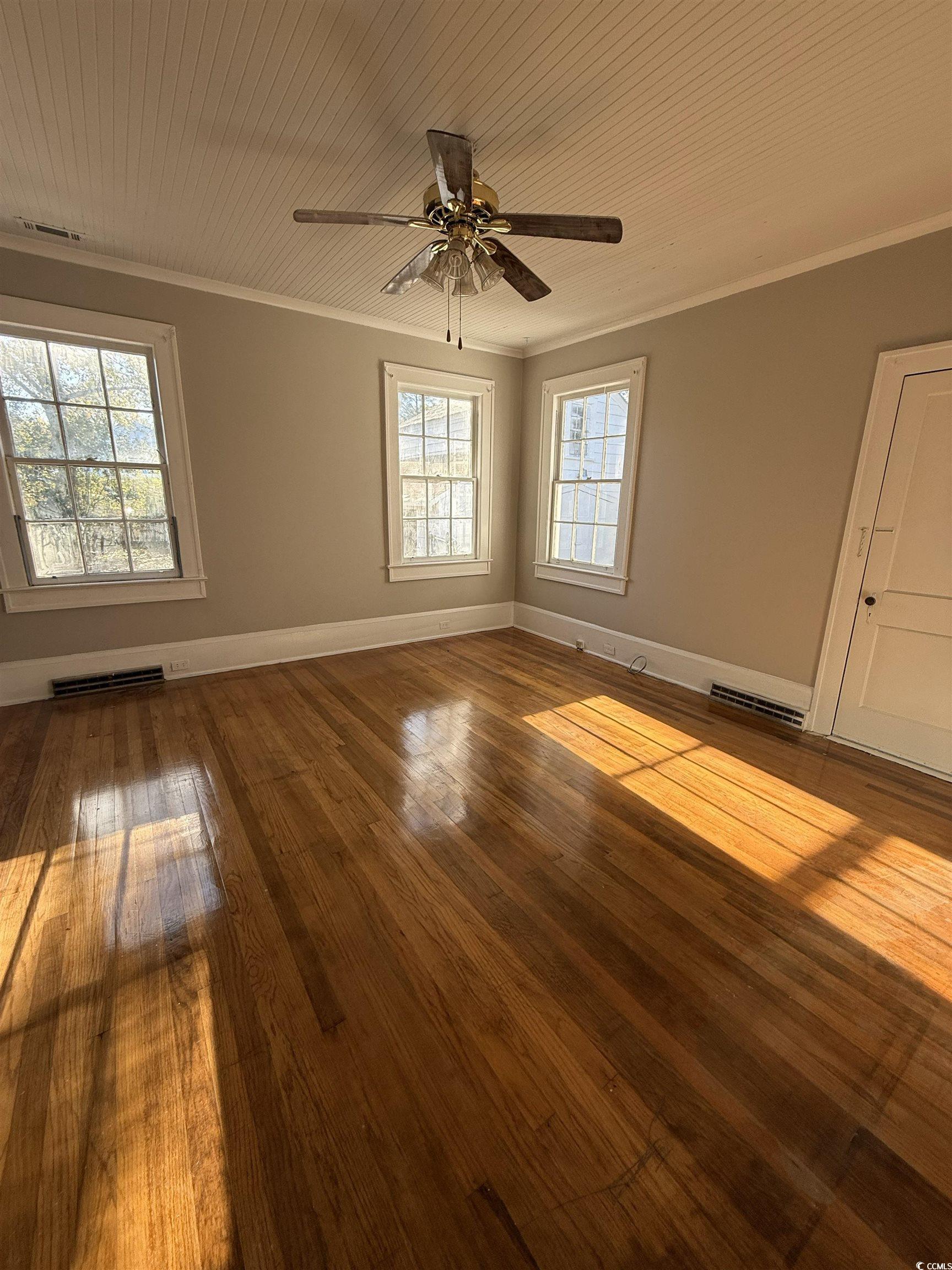 305 East Bamberg Street Latta, SC 29565 - Photo 3 of 13 Unfurnished room with wood ceiling, ornamental molding, hardwood / wood-style floors, and ceiling fan