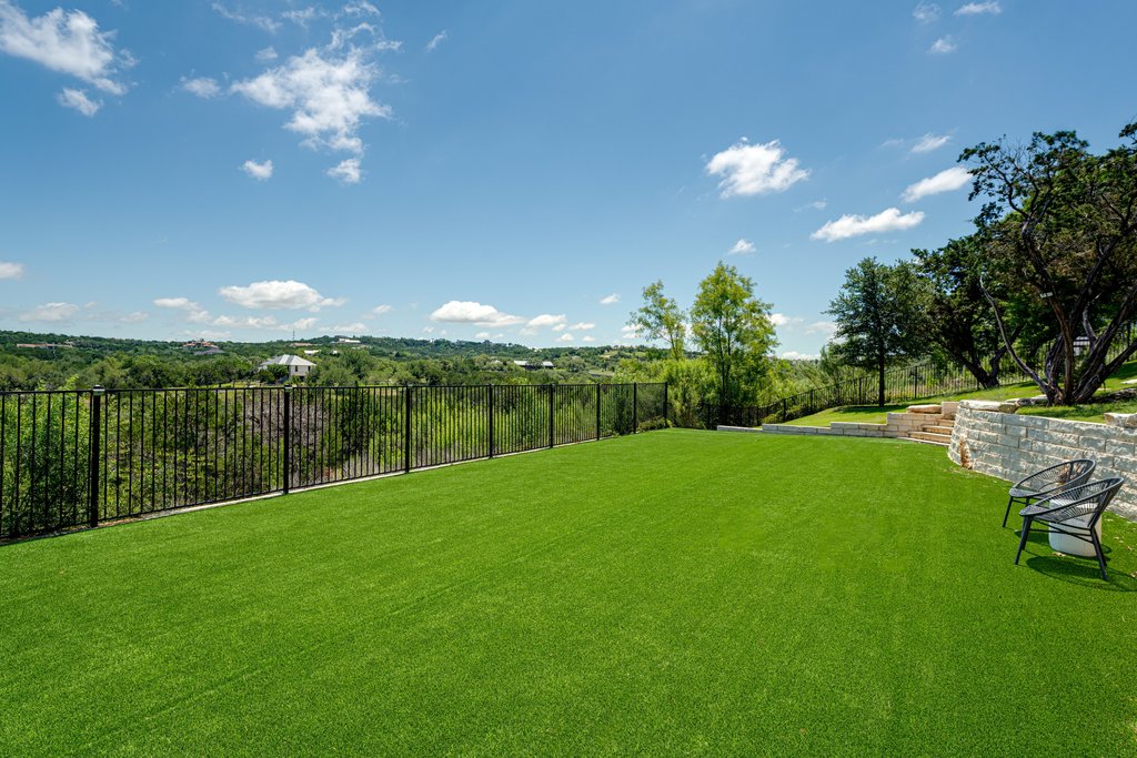 203 Lodestone Lane Austin, TX 78738 - Photo 6 of 40 Expansive green turf lawn with a black metal fence perimeter