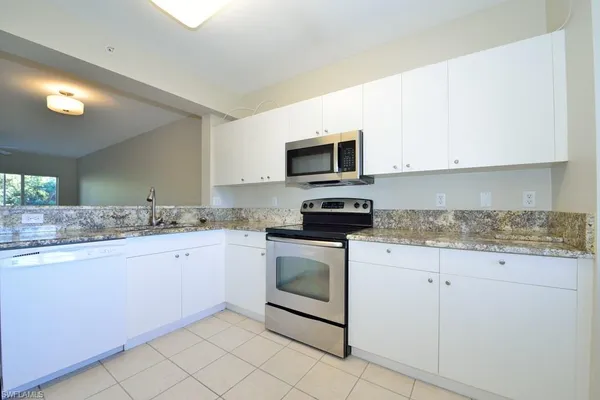 a kitchen with granite countertop white cabinets stainless steel appliances and a sink