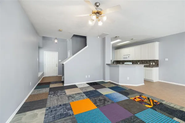a view of an empty room with kitchen appliances and a ceiling fan