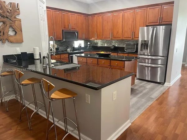 a kitchen with stainless steel appliances granite countertop a refrigerator a stove a sink and a microwave